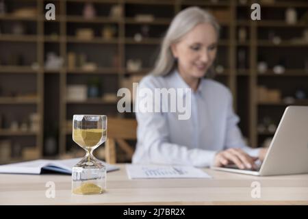 Sandglas aus nächster Nähe auf dem Arbeitstisch einer Geschäftsfrau Stockfoto