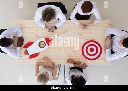 Team von Geschäftsleuten mit Raketenanvisierung auf rotes Ziel am Besprechungstisch, Planung des zukünftigen Startup-Konzepts Stockfoto