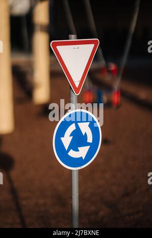 Verkehrsschilder auf dem Spielplatz in der Mini-Stadt für Kinder. Toy City. Verkehrsschild am Kreisverkehr abbiegen Stockfoto