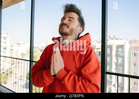 Gläubiger, junger Mann umklammelte die Hände, beteten und sendenden positive Energie, Meditation und religiösen Glauben Stockfoto