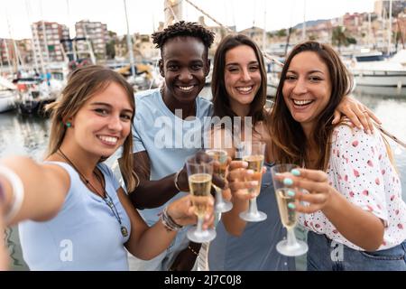 Eine Gruppe von Menschen aus verschiedenen Rassen, die gemeinsam Champagner auf dem Boot trinken Stockfoto