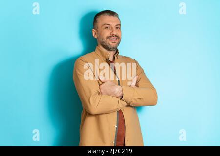 Schöner Mann Mittleren Alters, Der Über Dem Hintergrund Des Blue Studios Posiert Stockfoto