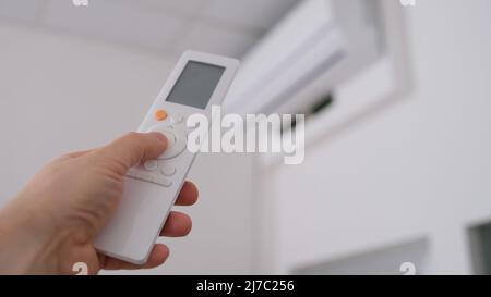 Person hält die Fernbedienung der Klimaanlage Stockfoto
