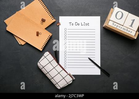 Leere To-do-Liste, Notizbuch, Kalender und Etui mit Schreibwaren auf dunklem Hintergrund Stockfoto