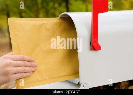 Frau bekommt Brief aus dem Briefkasten im Park, Nahaufnahme Stockfoto