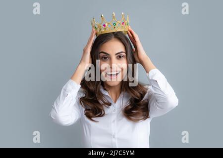 Portrait der Arroganz Frau mit goldener Krone auf dem Kopf, Führung und Erfolg. Attraktive reiche arrogante Mädchen tragen Krone isoliert über grau Stockfoto