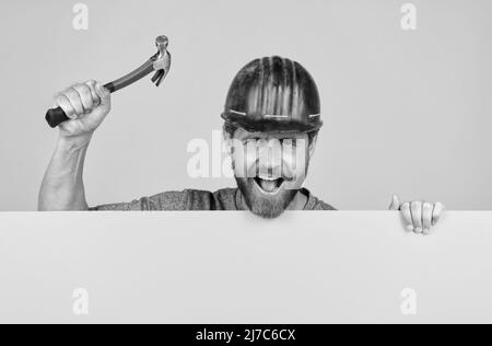 Ankündigung. Glücklicher Arbeitstag. Glücklicher reifer Mann im Helm mit Hammer. Stockfoto