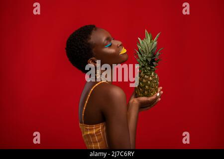 Profilportrait einer afroamerikanischen Frau mit Ananas Stockfoto