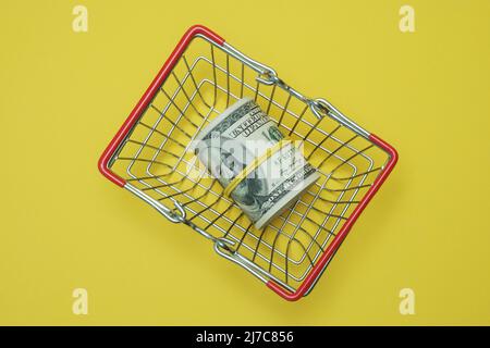 In einen Schlauch gerollte Dollars liegen in einem Einkaufskorb. Stockfoto