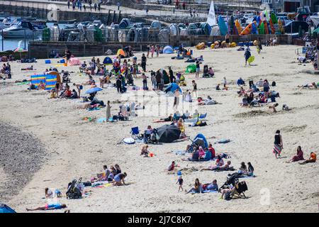 Lyme Regis, Dorset, Großbritannien. 8. Mai 2022. Wetter in Großbritannien: Urlauber und Sonnenanbeter strömen zum belebten Strand des Badeortes Lyme Regis, um heißen Sonnenschein und klaren blauen Himmel zu genießen, während die Hitzewelle im Mai anhält. Es wird nächste Woche mit Temperaturen von bis zu 26 Grad Celsius an der Südküste noch heißer werden. Kredit: Celia McMahon/Alamy Live Nachrichten. Stockfoto