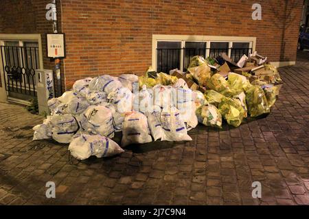 Abfälle und Recycling-Säcke in einem Stapel warten auf die Abholung. Überfließende Abfälle am Tag der Müllabfuhr (Ixelles, Belgien) Stockfoto