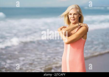 Reife Frau genießt ihre Freizeit mit Blick auf das Meer vom Ufer des Strandes. Stockfoto