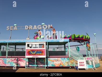 John-Henry Roper (links) und Kevin Morris polieren den Seedrachen unter blauem Himmel auf dem Messegelände an einem sonnigen Morgen in Hunstanton, Norfolk, Großbritannien, am 5. Mai 2022. Stockfoto