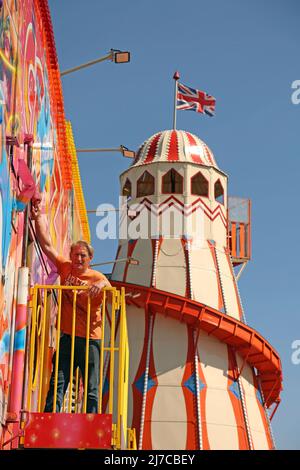 John-Henry Roper poliert das Crazy House unter blauem Himmel auf dem Messegelände an einem sonnigen Morgen in Hunstanton, Norfolk, Großbritannien, am 5. Mai 2022. Die Familie von Herrn Roper ist seit über 50 Jahren auf dem Messegelände. Stockfoto