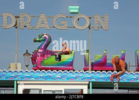 John-Henry Roper (links) und Kevin Morris polieren den Seedrachen unter blauem Himmel auf dem Messegelände an einem sonnigen Morgen in Hunstanton, Norfolk, Großbritannien, am 5. Mai 2022. Stockfoto