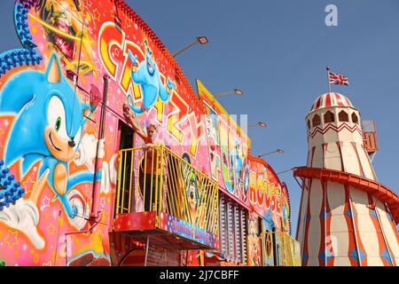 John-Henry Roper poliert das Crazy House unter blauem Himmel auf dem Messegelände an einem sonnigen Morgen in Hunstanton, Norfolk, Großbritannien, am 5. Mai 2022. Die Familie von Herrn Roper ist seit über 50 Jahren auf dem Messegelände. Stockfoto