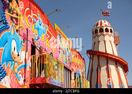 John-Henry Roper poliert das Crazy House unter blauem Himmel auf dem Messegelände an einem sonnigen Morgen in Hunstanton, Norfolk, Großbritannien, am 5. Mai 2022. Die Familie von Herrn Roper ist seit über 50 Jahren auf dem Messegelände. Stockfoto