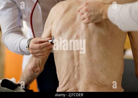 Ein Sanitäter und ein Sanitäter überprüfen die Gesundheit eines älteren männlichen Patienten mit Stethoskop. Stockfoto