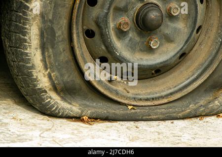 Nahaufnahme eines Platten Reifens eines alten rostigen Autos Stockfoto