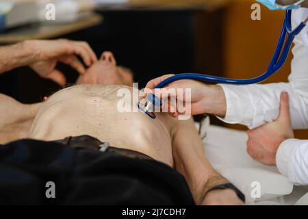 Ein Arzt überprüft die Gesundheit eines älteren männlichen Patienten mit Stethoskop. Stockfoto