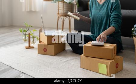 Entrepreneur mit Rechner mit Bleistift in der Hand, Berechnung der finanziellen Kosten im Home Office, Online-Markt Verpackung Box Lieferung, Startup Stockfoto