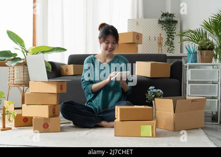 Entrepreneur mit Rechner mit Bleistift in der Hand, Berechnung der finanziellen Kosten im Home Office, Online-Markt Verpackung Box Lieferung, Startup Stockfoto