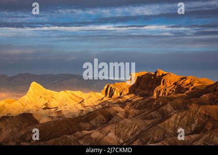 Sonnenaufgang hellt die Gipfel am Zabriskie Point im Death Valley, Kalifornien, auf. Stockfoto