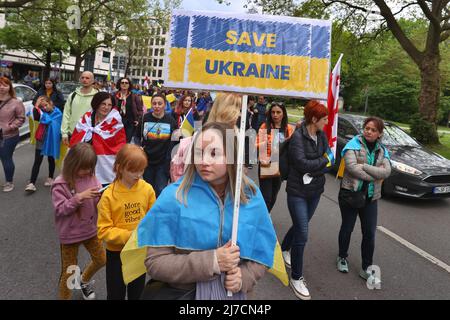 08. Mai 2022, Bayern, München: Ein Teilnehmer einer Kundgebung gegen den Krieg in der Ukraine hält während eines marsches durch das Stadtzentrum ein Schild mit der Aufschrift „Save Ukraine“. Foto: Karl-Josef Hildenbrand/dpa Stockfoto