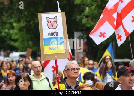 08. Mai 2022, Bayern, München: Ein Teilnehmer einer Kundgebung gegen den Krieg in der Ukraine hält während eines demonstrationsmarsches durch die Innenstadt ein Schild mit dem Bild eines Schweins und den Worten "nach Den Haag". Foto: Karl-Josef Hildenbrand/dpa Stockfoto