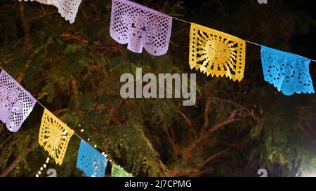 Papel picado Girlande, perforierte Papiertaschentücher-Flaggen. Mexikanische farbenfrohe ethnische Einrichtung für Urlaub, Karneval, Party oder Fiesta. Festival Straßendekoration, Cinco de Mayo, Day of Dead oder Dia de Muertos. Stockfoto