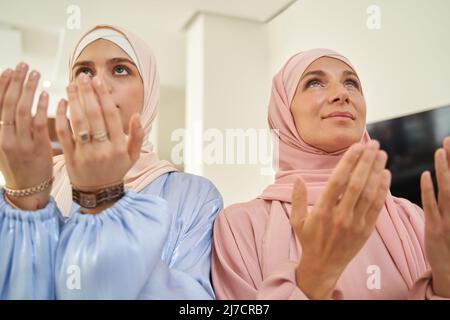 Zwei muslimische Frauen beten zu Hause zusammen Stockfoto