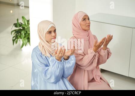 Muslimische Frauen in Hijab beten zu Hause Stockfoto