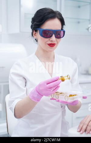 Weibliche Kosmetikerin hält Teile der Laser-Haarentfernungsvorrichtung Stockfoto
