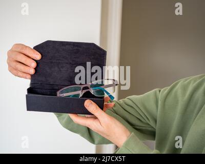 Junge Frau, die mit ihrer reparierten Glasbrille in einem Fall aus einem Optiker herauskommt Stockfoto