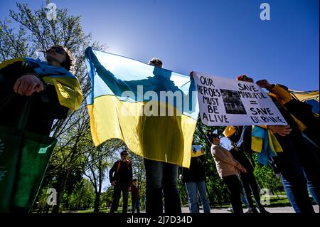 ZAPORIZHZHIA, UKRAINE - 7. MAI 2022 - Aktivisten mit ukrainischen Fahnen halten Plakate während einer Kundgebung, um die globale Gemeinschaft aufzufordern, bei der Evakuierung zu helfen Stockfoto