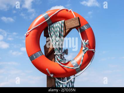 Lifebuoy auf blauem Himmel Hintergrund. Rettungsausrüstung. Sicherheit während des Wasserausflugs und dringendes Hilfekonzept. Hochwertige Fotos Stockfoto