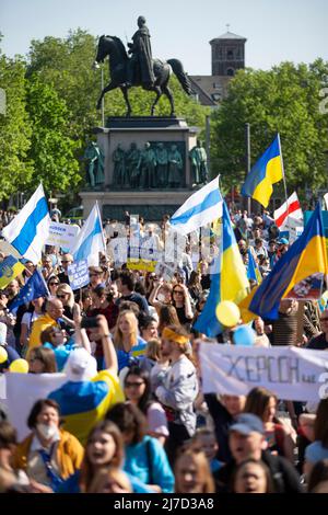 08. Mai 2022, Nordrhein-Westfalen, Köln: Teilnehmer der Friedensdemonstration „Solidarität mit der Ukraine“ stehen bei der Abschlusskundgebung auf dem Kölner Heumarkt mit Fahnen schwenkend. Foto: Thomas Banneyer/dpa Stockfoto