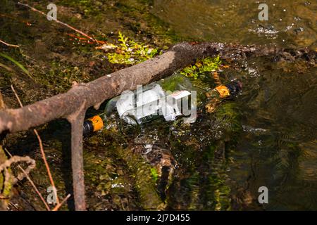 Weinflaschen wurden in einem Bach entleert und verschmutzen nun die Umwelt Stockfoto