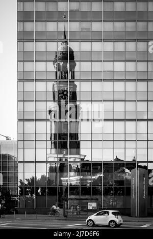 Hamburg, Deutschland - 18. August 2012: Der alte Glockenturm der St. Michaelskirche spiegelt sich in einem modernen Büroturm in Hamburg wider Stockfoto