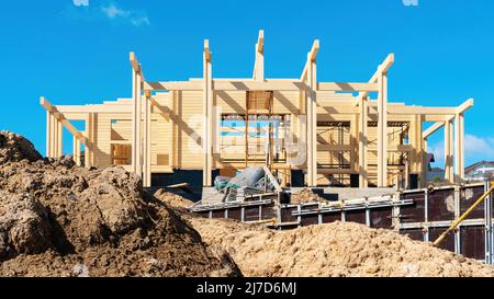 Bau eines Holzhauses aus verleimtem Profilholz in der Frühjahrssaison. Die Verwendung von Schalungen für die Betonierung der Terrasse, das Fundament der Stockfoto