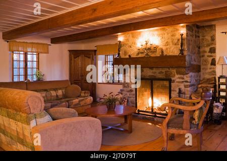 Beleuchteter Steinkamin und antike Möbel im Wohnzimmer im 1800s Blockhaus. Stockfoto