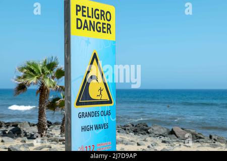 Warnschild am Strand über hohe Wellen, Spanisch und Englisch. Stockfoto