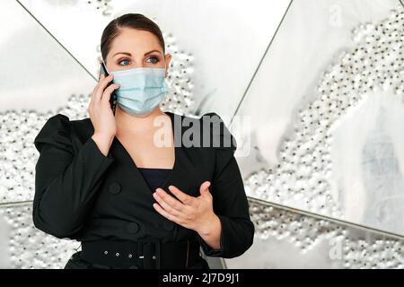 Geschäftsfrau mit Gesichtsmaske beim Telefonieren im Büro. Stockfoto