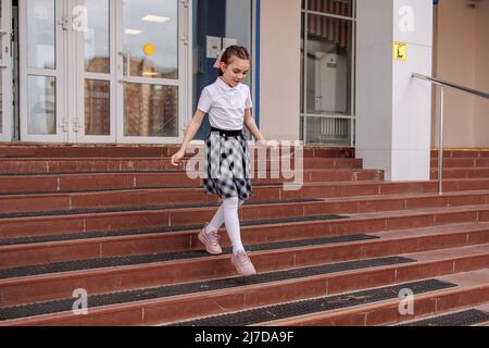 Zurück zur Schule. Mädchen in Schuluniform gehen zur Schule. Beginn des Unterrichts. Erster Herbsttag. Grundschüler. Hochwertige Fotos Stockfoto