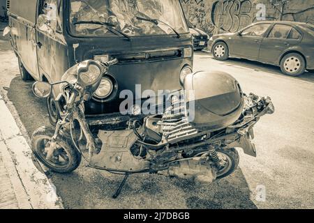 Altes Schwarz-Weiß-Bild eines alten schwarz zerbrochenen schmutzigen VW-Busses Volkswagen-Auto rostend und zerbrochenen Motorroller am Straßenrand in Playa del Carme Stockfoto