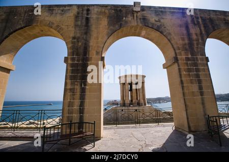 Blick auf das Kriegsdenkmal der Belagerer Bell von den unteren Arkaden der Barrakka-Gärten in La Valletta Stockfoto