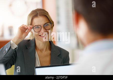 Männlicher Optiker hilft Frau, Gläser im optischen Laden zu wählen Stockfoto