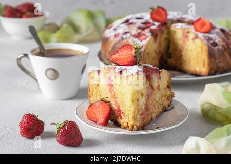 Charlotte Pie Erdbeeren mit einem geschnittenen Stück und auch eine Tasse Kaffee auf hellgrauem Tisch Stockfoto