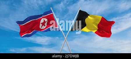 Zwei gekreuzte Fahnen Nordkoreas und Belgiens winken im Wind bei bewölktem Himmel. Konzept der Beziehung, des Dialogs, des Reisens zwischen zwei Ländern. 3D illustre Stockfoto