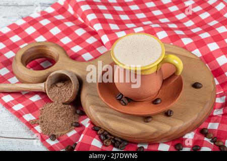 Traditioneller türkischer Dibek-Kaffee in Kaffeetasse auf Holztisch. Türkischer Dibek-Kaffee grindete in einem großen Steinmörtel mit der traditionellen Hand Stockfoto